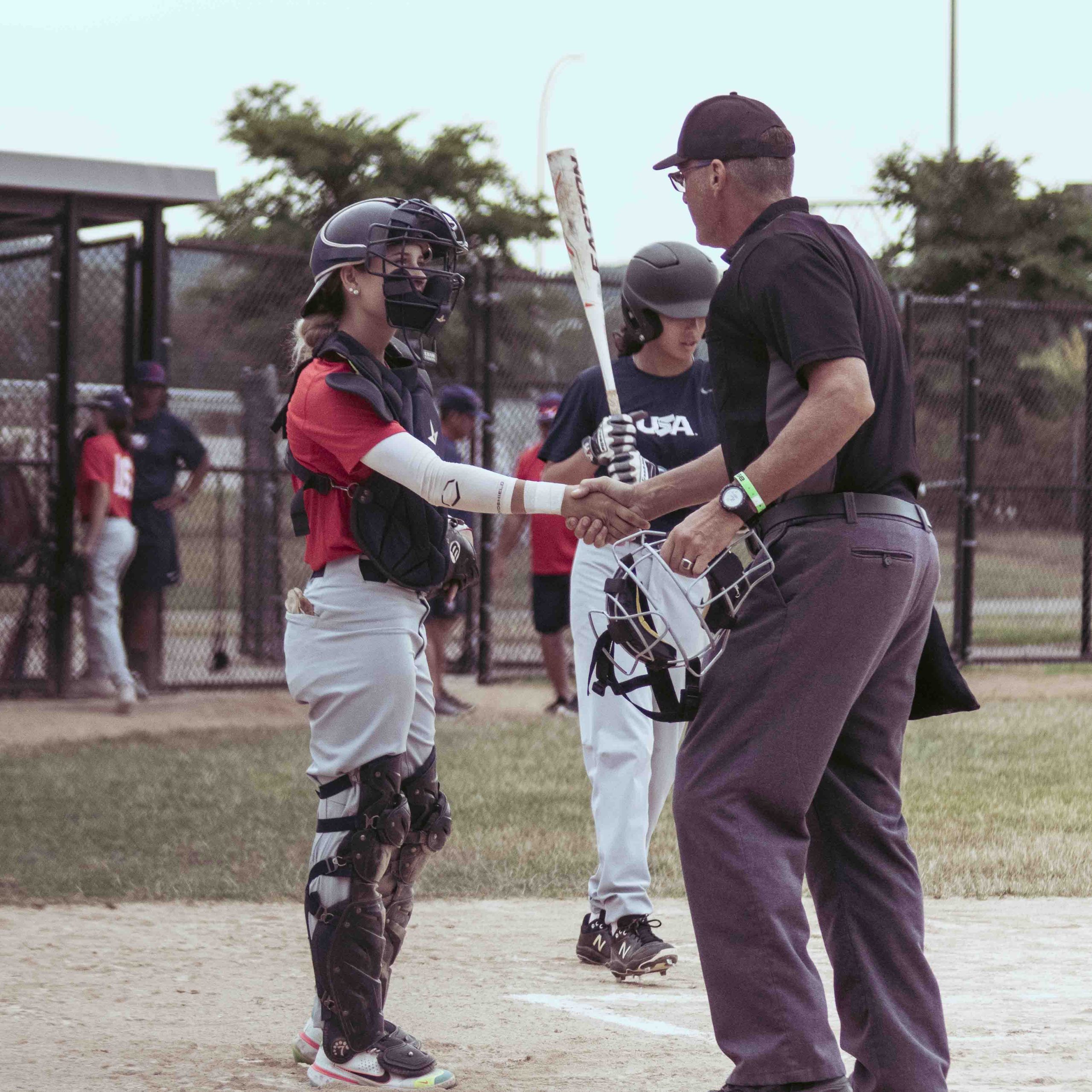 A catcher and umpire shake hands before a game of ball.